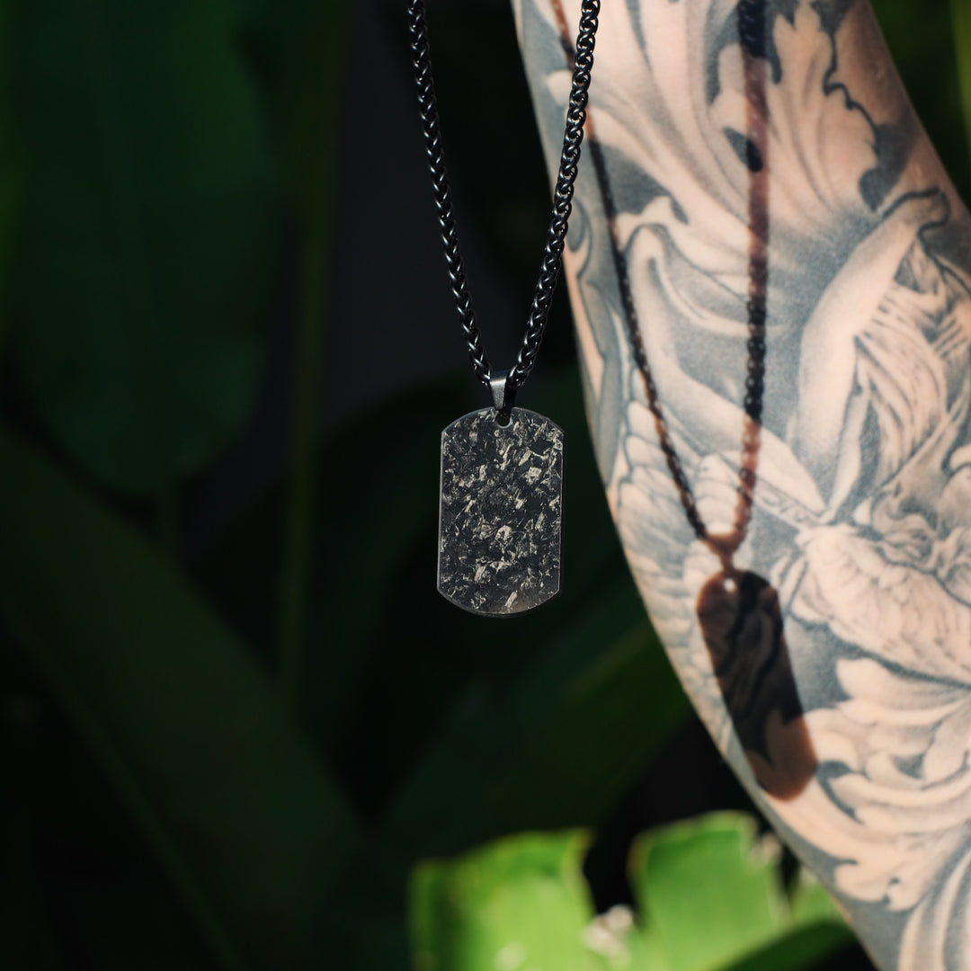 Forged Dogtag Chain auf weißem Shirt getragen, mit schwarzem Armband kombiniert